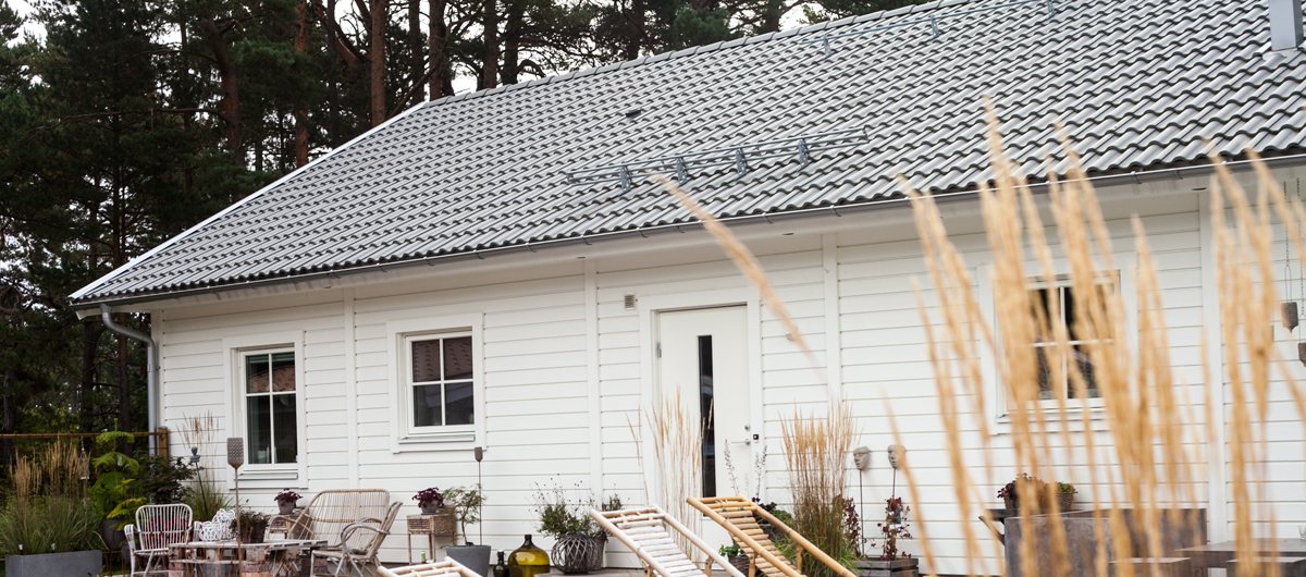 Vit villa med trädäck och solstolar bland tallarna